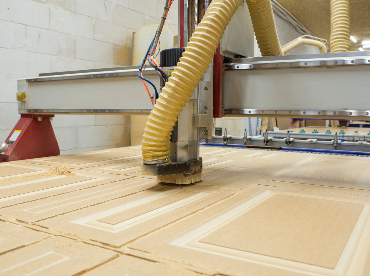 CNC milling machine cutting designs into solid wood panels 